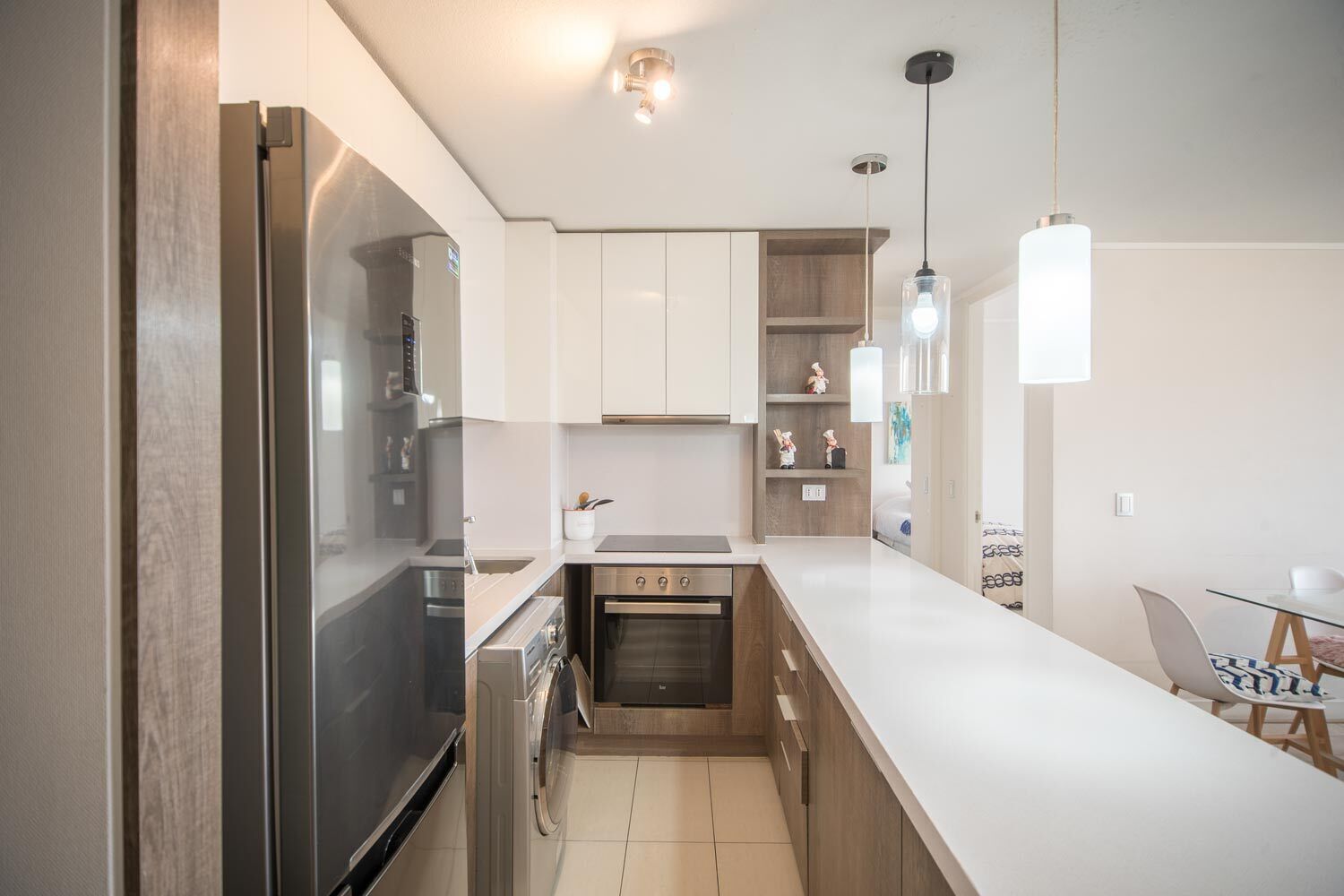 A modern kitchen with stainless steel appliances, wooden cabinets, and pendant lighting.