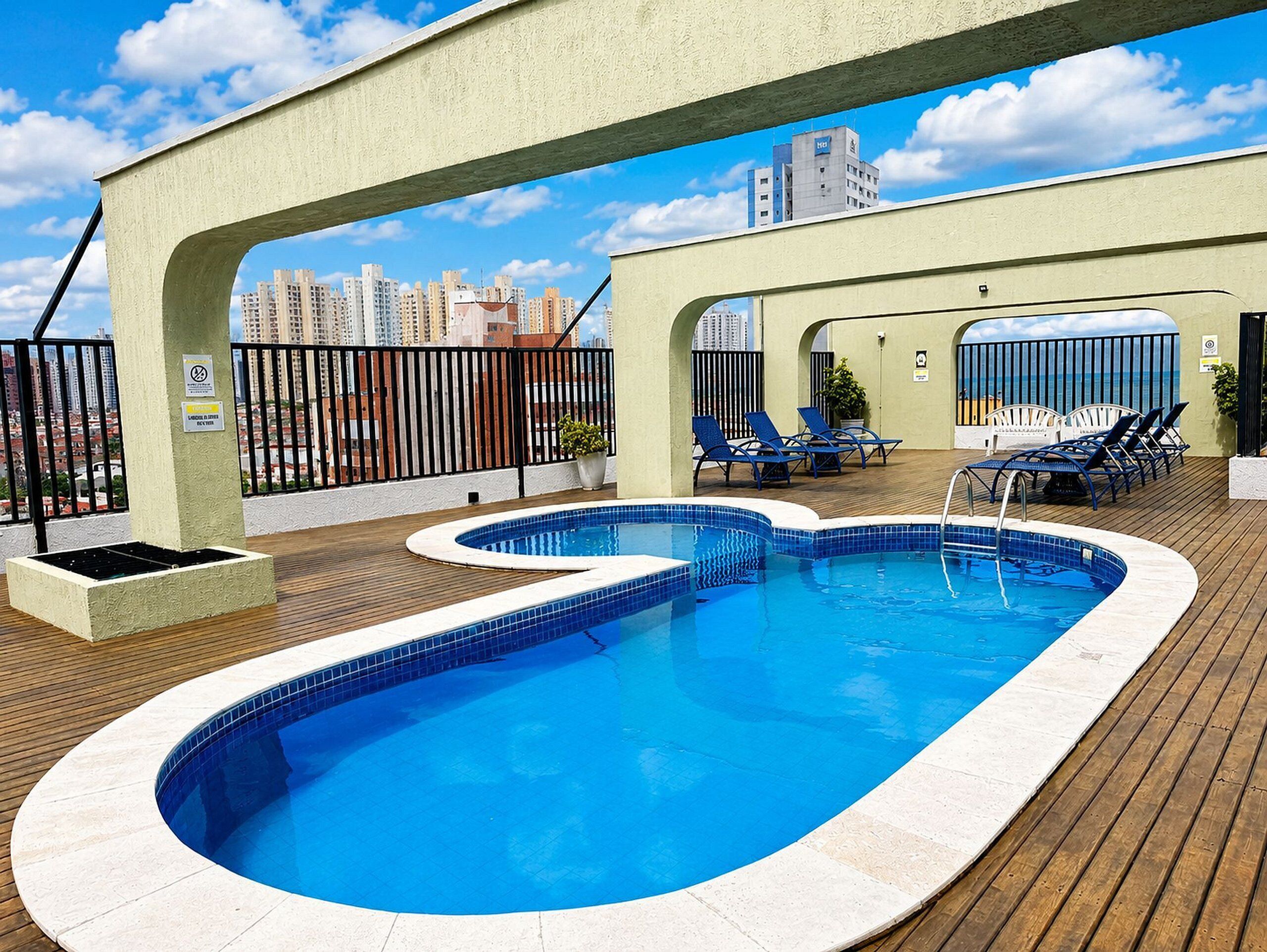 Piscina no terraço com vista para o horizonte da cidade, espreguiçadeiras e um deck de madeira.