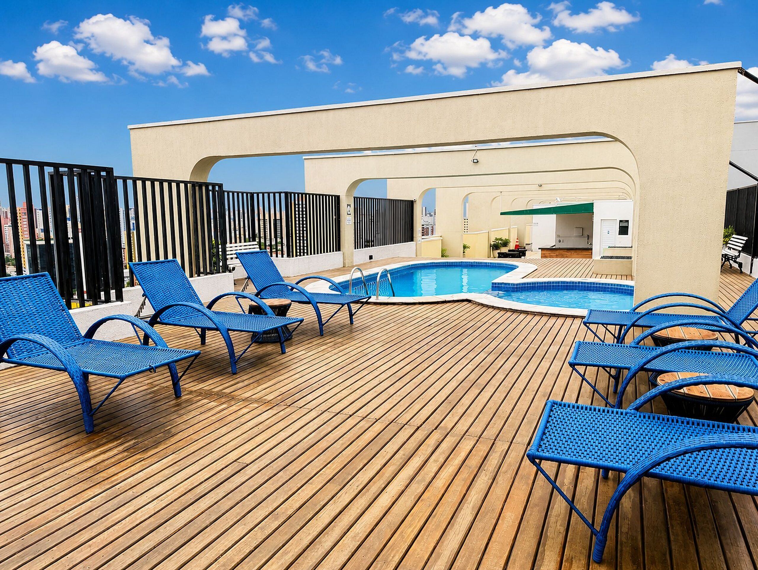 Area piscina sul tetto con poltrone da relax blu e un solarium in legno.