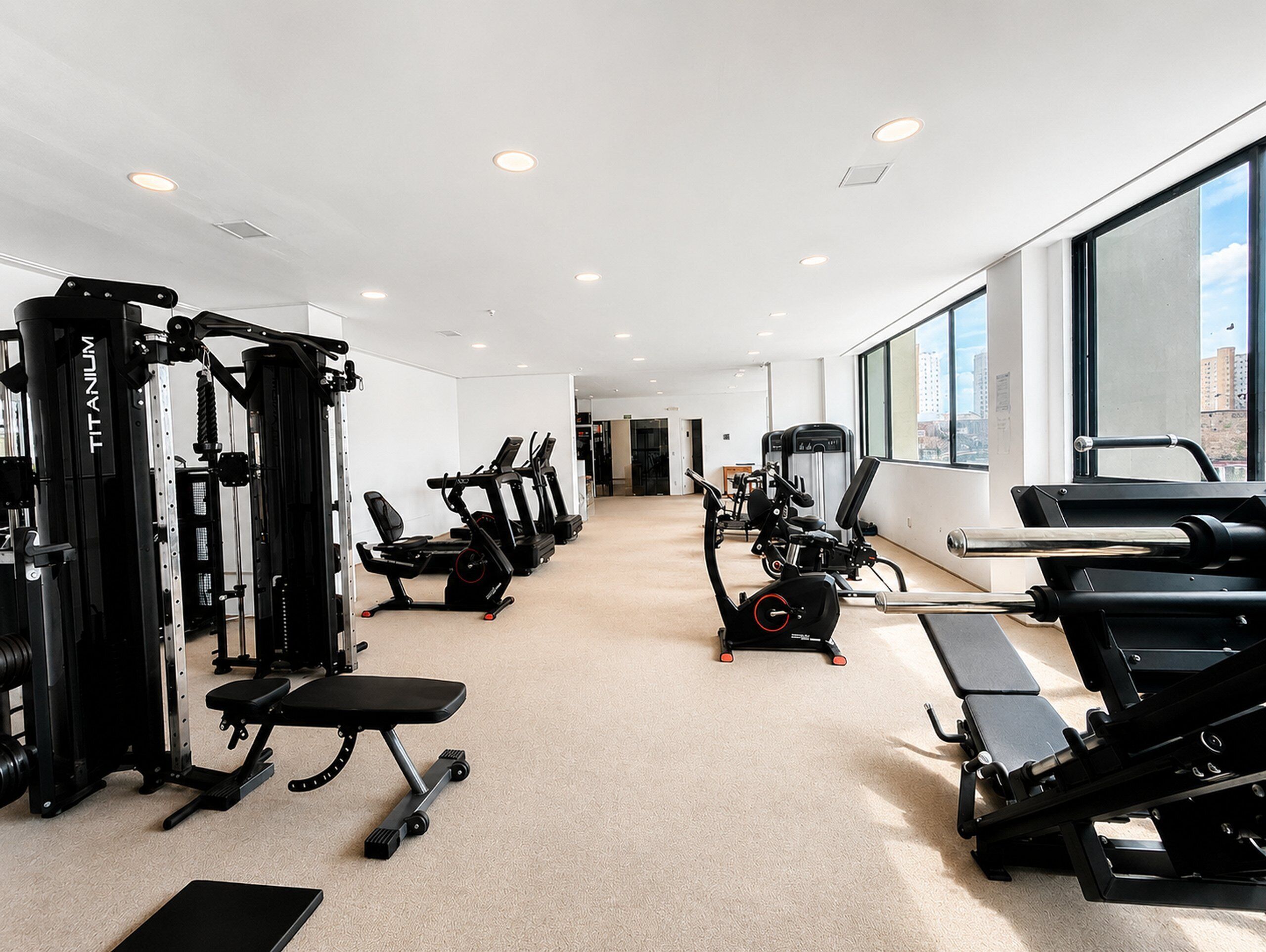 Una palestra con diverse attrezzature per esercizi, una panca e un pavimento rivestito di moquette.
