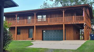 Une maison en bois à deux étages, dotée d’un balcon, d’un garage et d’un drapeau.