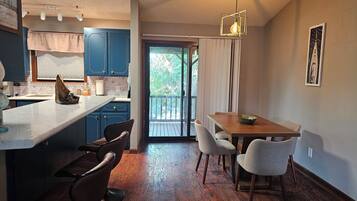 Une cuisine moderne avec des meubles bleus, une table à manger en bois et une vue sur l’extérieur.