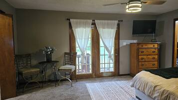 Une chambre à coucher comprenant un lit, une commode, une chaise, une petite table avec une plante et un ventilateur de plafond.