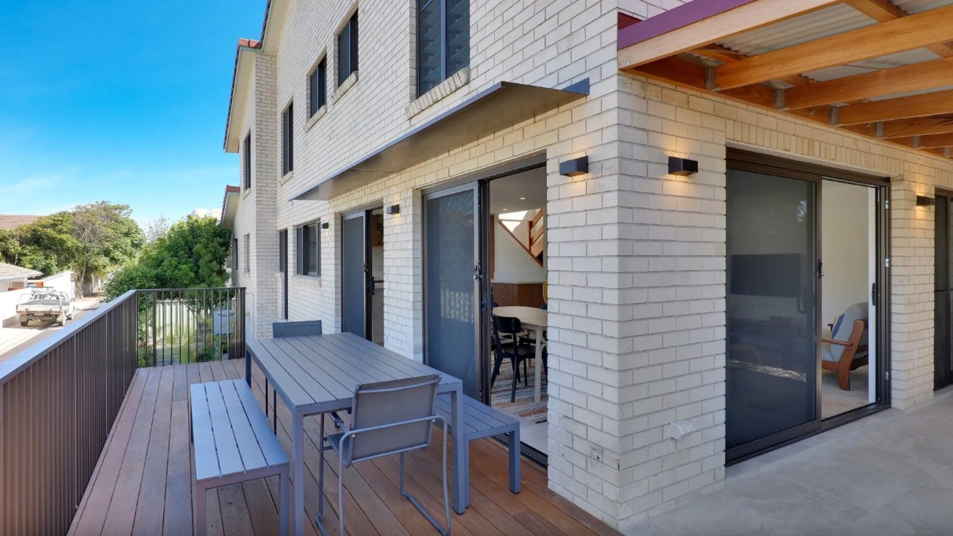 A modern building with a deck, outdoor seating, and a glass door entrance.