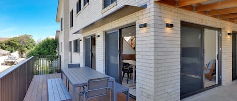 A modern building with a deck, outdoor seating, and a glass door entrance.