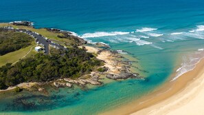 Eine Luftaufnahme einer Küstenlandschaft mit Parkplatz, Strand und felsigem Gelände.