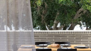 A dining area with a brick wall, a wooden table, and black chairs. - The Avenue ~ Sawtell Village Prime Location (Sawtell)