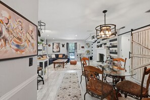 Uma sala de estar moderna com uma mesa de jantar de vidro, um sofá e um grande quadro abstrato.