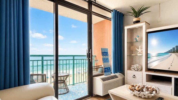 Een hotelkamer met balkon, televisie, een bank, een tafel met decoratieve objecten en een plant.