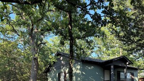 Ein rustikales Blockhaus mit Veranda, umgeben von Bäumen und Sitzgelegenheiten im Freien.