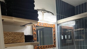 Ein Badezimmer mit einem weißen Waschbecken, einem Spiegel mit orangenem Rahmen, einer Toilette und einem Duschbereich.