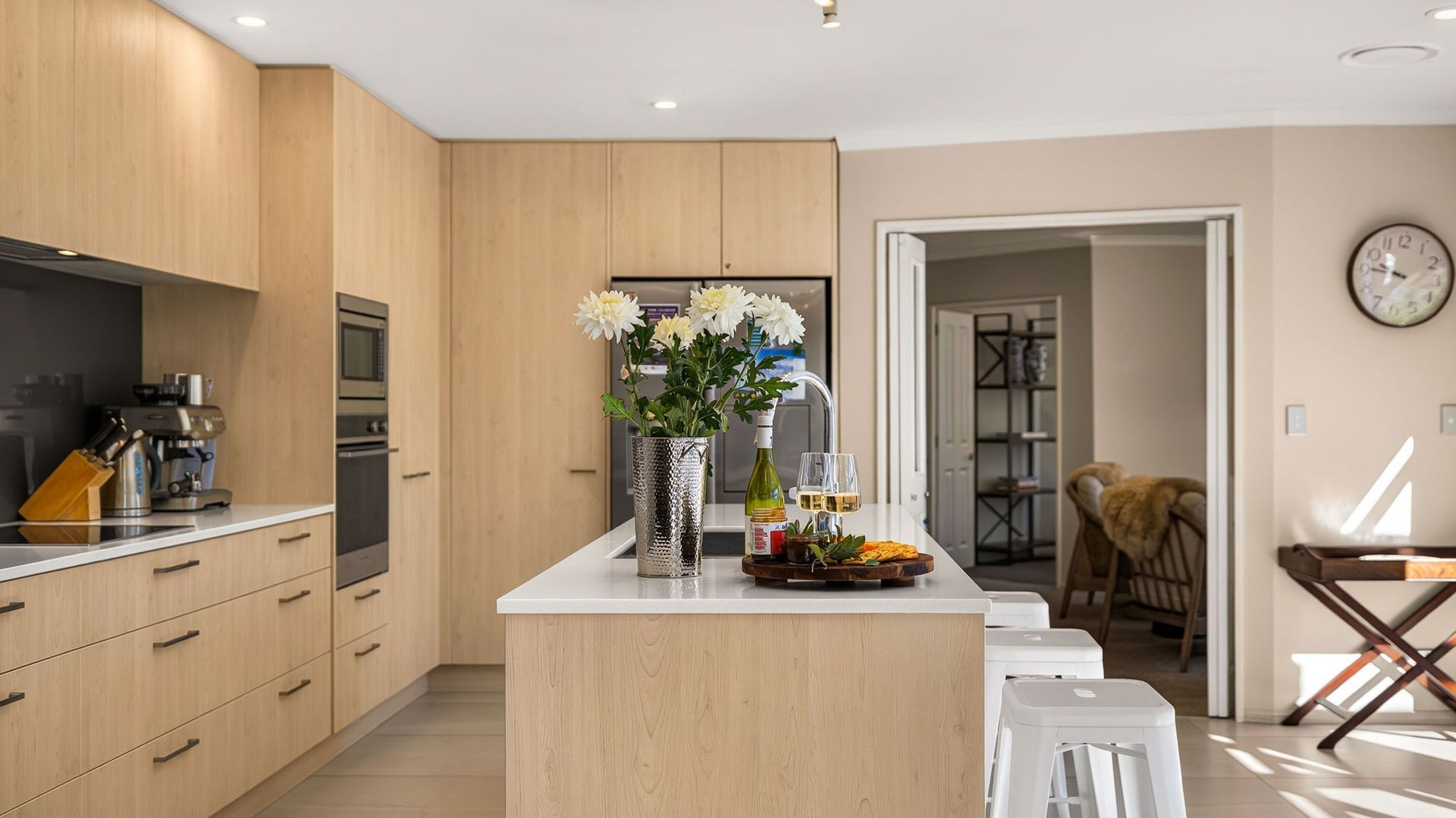 A modern kitchen with wooden cabinets, a central island, and a dining area with a chair.