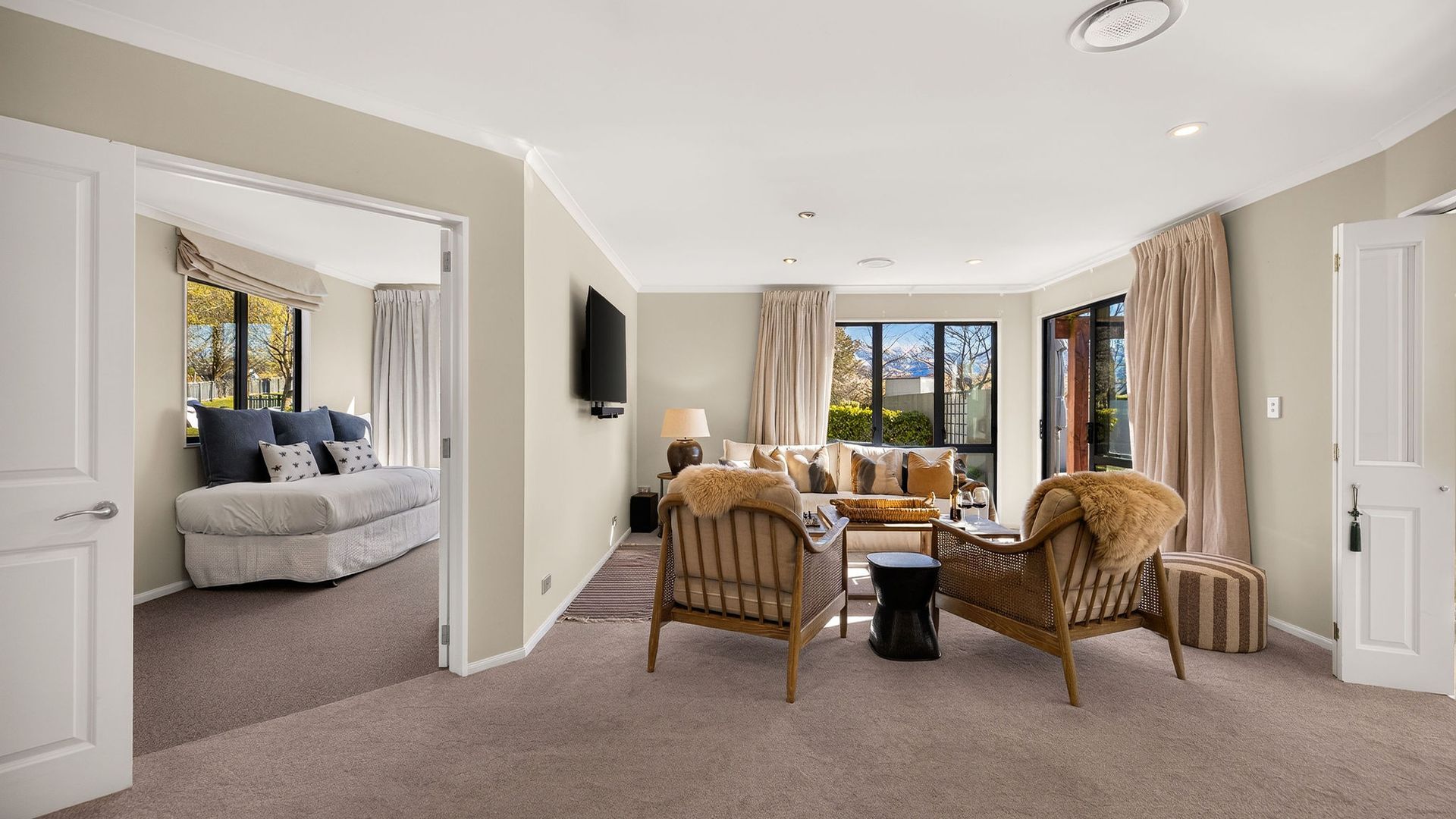A spacious living room with a sofa, two armchairs, a coffee table, and a television.