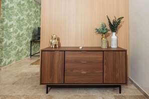 A wooden cabinet with drawers, a small elephant figurine, and two vases with plants. - Stylish Apartment | Rooftop Pool & King Bed (Cancún)