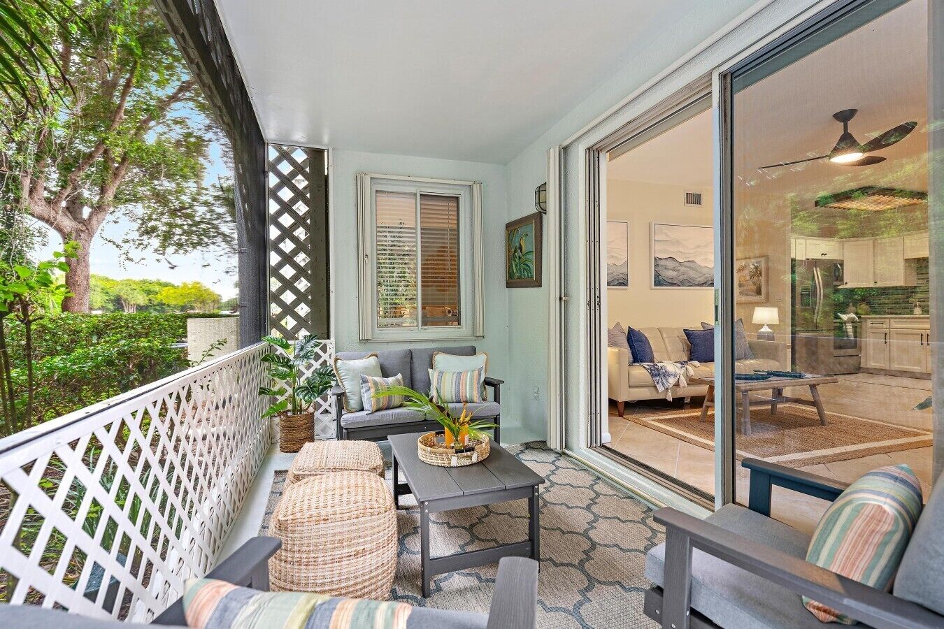 A covered outdoor seating area with a sofa, chairs, a table, and a potted plant.