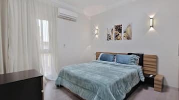 Une chambre à coucher comprenant un lit, des tables de chevet, des lampes fixées au mur et des œuvres d’art.
