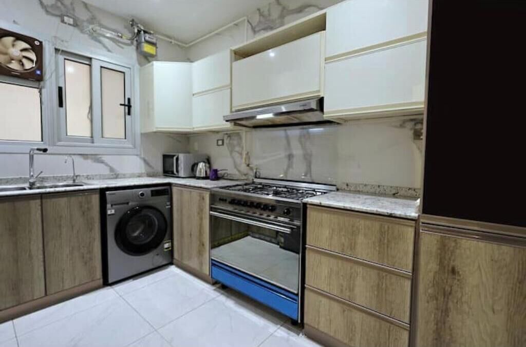 Cozinha compacta com máquina de lavar, fogão e micro-ondas.