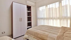 A bedroom with a bed, a wardrobe, and a window with curtains.