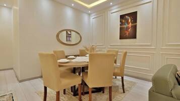 Uma sala de jantar com uma mesa redonda, seis cadeiras, um espelho e uma obra de arte emoldurada na parede.