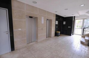 A spacious hallway with a tiled floor, a door on the left, and a staircase on the right.