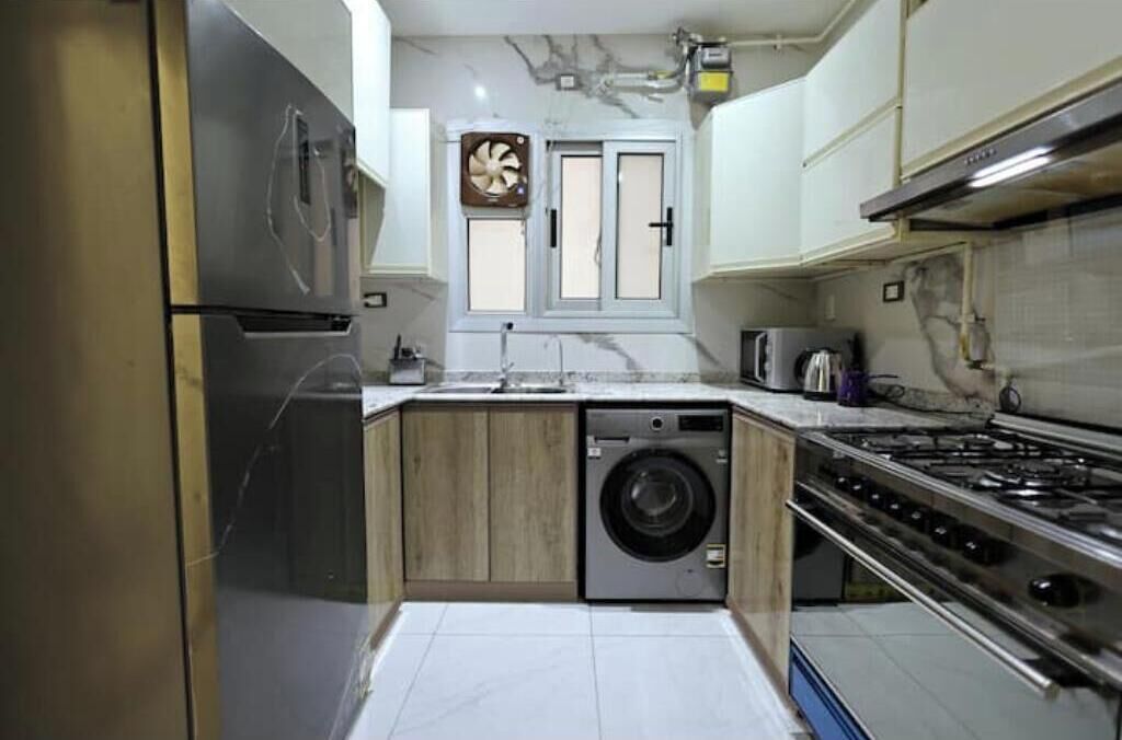 Uma cozinha compacta com máquina de lavar embutida, fogão e micro-ondas.