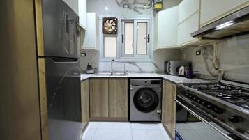 Uma cozinha compacta com máquina de lavar embutida, fogão e micro-ondas.
