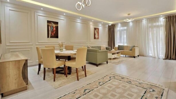 A spacious living room with a dining area, a sofa set, and a chandelier.