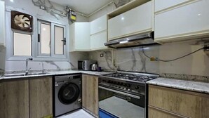 A compact kitchen with a built-in washer, a gas stove, and wooden cabinets.