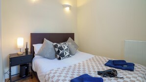 Una habitación de hotel con cama, mesita de noche, lámpara y radiador.