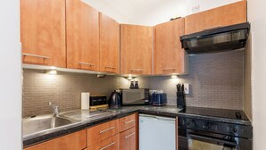Una cocina con armarios de madera, un lavamanos de acero inoxidable, microondas, tostadora y lavavajillas.