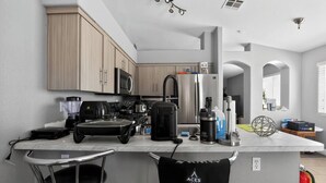 Een moderne keuken met roestvrijstalen apparatuur, een centraal eiland en barkrukken.