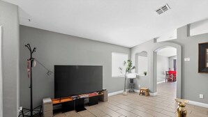 Een moderne woonkamer met een flatscreen televisie, een salontafel en een plant.
