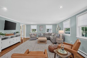 A living room with a television, sofas, a coffee table, and a fireplace. - Cape Cod Escape | Near Beaches | Play Area (Osterville)