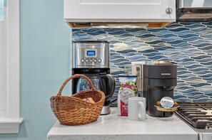 A kitchen with a coffee maker, a basket, a mug, and a bag of coffee. - Cape Cod Escape | Near Beaches | Play Area (Osterville)
