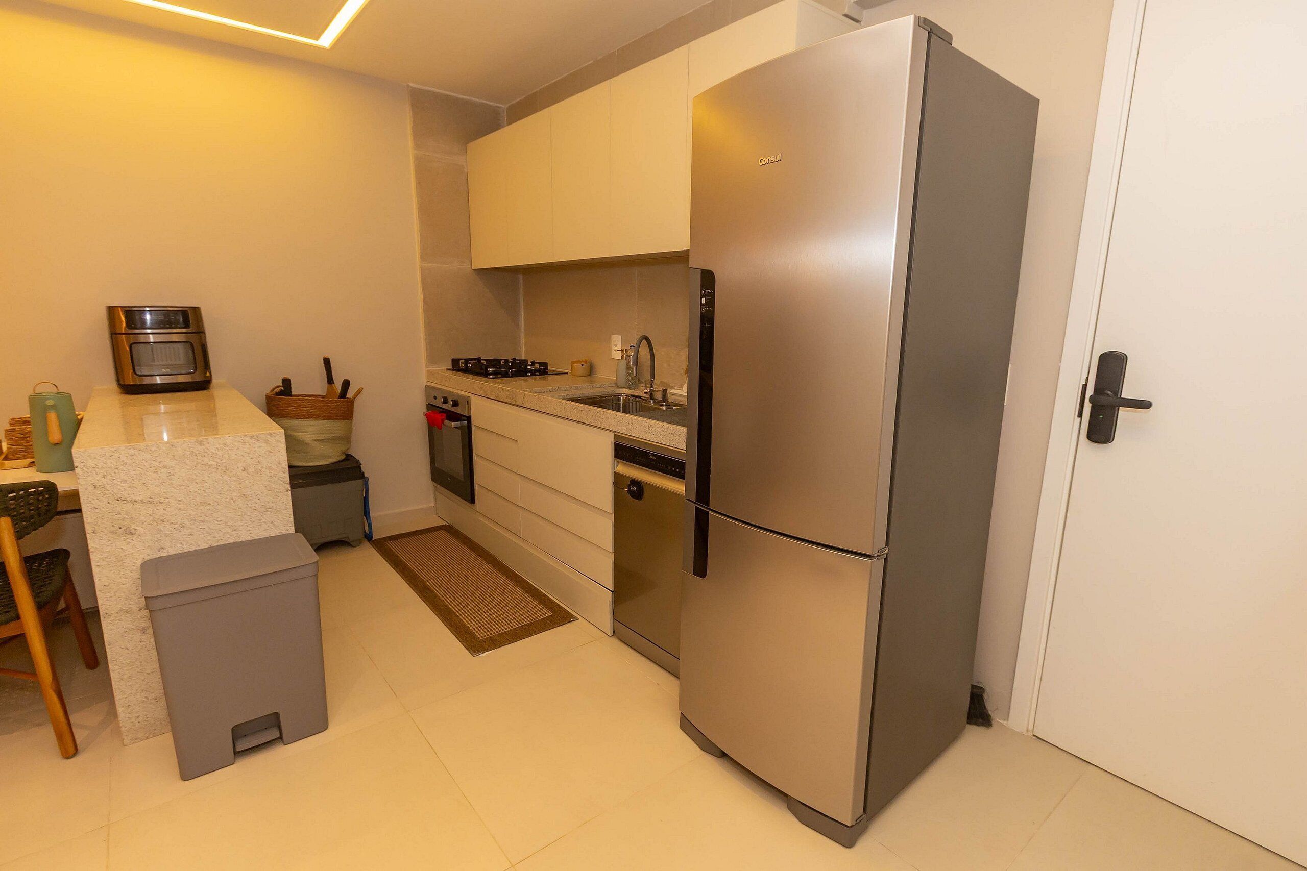A modern kitchen with a stainless steel refrigerator, a built-in oven, and a sink.
