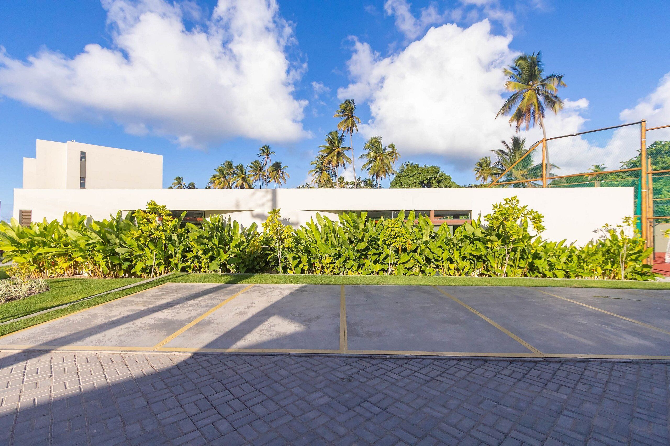 Un edificio moderno con techo plano, rodeado de exuberante vegetación y palmeras.