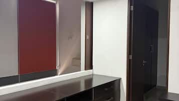 Una habitación moderna con un mueble oscuro de madera, un espejo grande y una puerta.