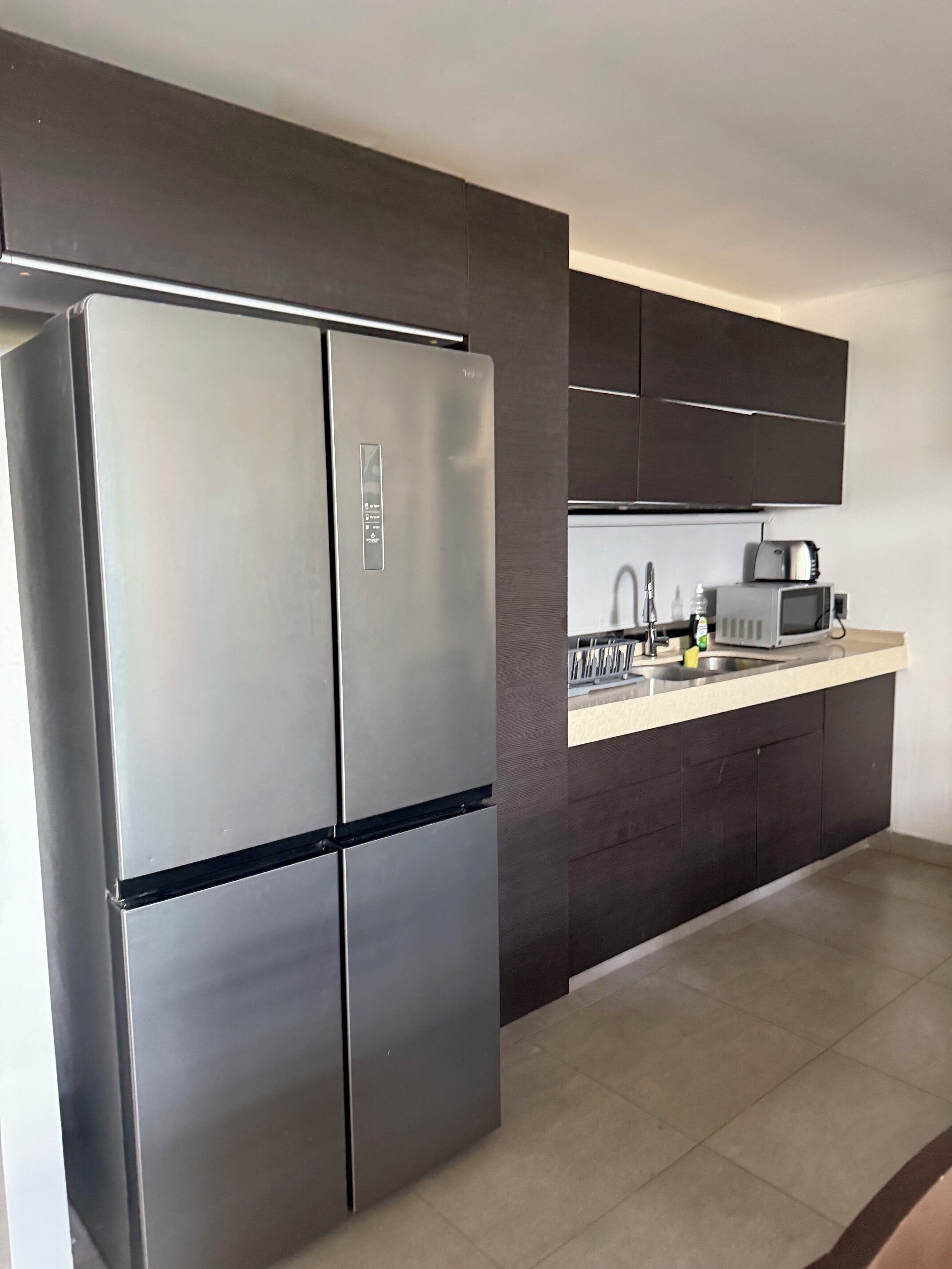 A modern kitchen with a stainless steel refrigerator, a microwave, and a sink.