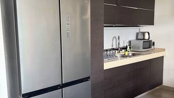 A modern kitchen with a stainless steel refrigerator, a microwave, and a sink.