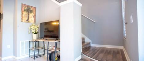A modern interior with a staircase, a dining area with a table and chairs, and a kitchen area.