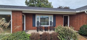 A residential building with a brick exterior, a covered porch with a table and chairs, and a window with shutters. - 3 Bedroom House - Family Friendly - Sleeps 6 (Ephrata)