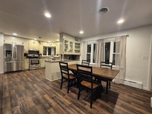 A modern kitchen with a central island, wooden flooring, and built-in cabinetry. - 3 Bedroom House - Family Friendly - Sleeps 6 (Ephrata)