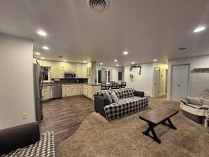 A spacious living area with a sofa, a coffee table, and a dining table. There is a kitchen with a microwave and cabinets. - 3 Bedroom House - Family Friendly - Sleeps 6 (Ephrata)
