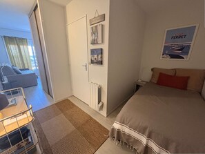 Une chambre à coucher comprenant un lit, une table de chevet, un tableau accroché au mur, une porte et une vue sur un balcon.