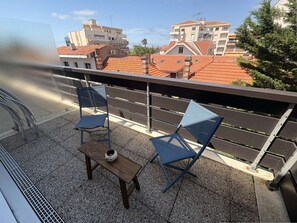 A balcony with two blue chairs, a small wooden table, and a white vase. - Studio flat + balcony, 150 metres from the Beach (ARCACHON)