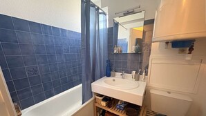 Une salle de bain avec une baignoire, un lavabo, des toilettes et un rideau de douche.