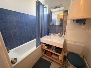 A bathroom with a bathtub, a sink, a toilet, and a shower curtain. - Studio flat + balcony, 150 metres from the Beach (ARCACHON)