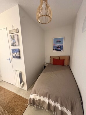 A bedroom with a bed, a radiator, a door, and a poster on the wall. - Studio flat + balcony, 150 metres from the Beach (ARCACHON)
