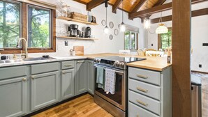 Una cocina con vigas de madera, una estufa y un lavabo.