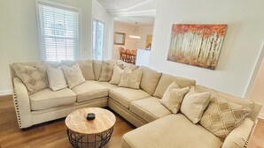 A living room with a sectional sofa, a round coffee table, and a ceiling fan.
